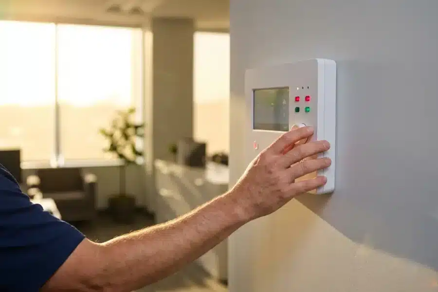 Beveiligingstechnicus bedient wit controlepaneel met rode en groene indicatielampjes in moderne kantooromgeving