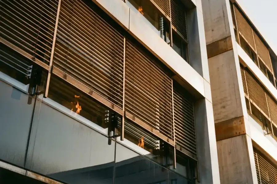 Modern kantoorgebouw met brandwerende glazen panelen en geïntegreerde horizontale zonwering, gefotografeerd vanuit lage hoek tijdens gouden uur