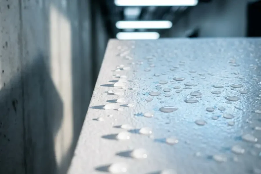 Waterdruppels op wit brandwerend paneel in moderne commerciële gang met betonnen muur en industriële verlichting